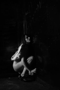 Dekoratif melek kanatları takan çıplak bir kadın. Karanlık arka planda poz veriyor.    