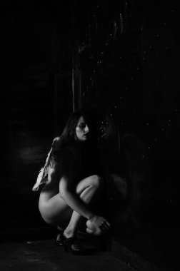 Dekoratif melek kanatları takan çıplak bir kadın. Karanlık arka planda poz veriyor.    