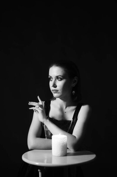 woman with makeup posing with candle on dark background, Halloween concept 