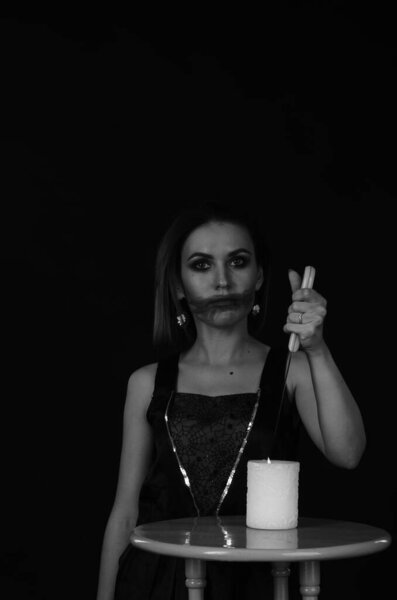 woman with creepy makeup holding knife over candle, Halloween concept 