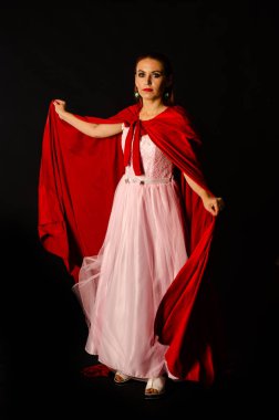 Stüdyoda kırmızı pelerinli güzel bir kadın var. Kırmızı Başlıklı Kadın. Dramatik ve fantastik çekim, modaya uygun tonlama. Bir prenses gibi..