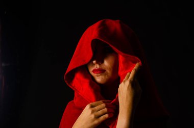 Stüdyoda kırmızı pelerinli güzel bir kadın var. Kırmızı Başlıklı Kadın. Dramatik ve fantastik çekim, modaya uygun tonlama. Bir prenses gibi..
