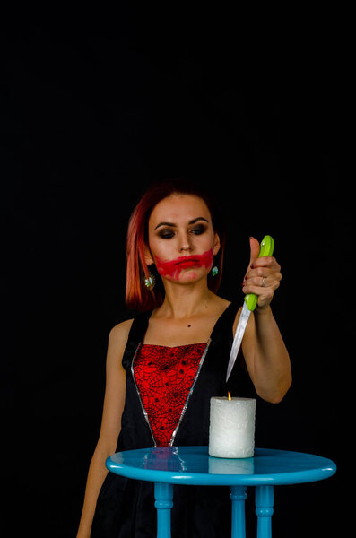woman with creepy makeup holding knife over candle, Halloween concept 