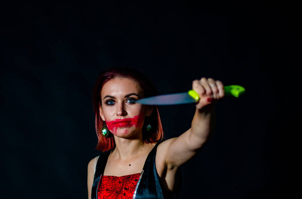woman with creepy makeup holding knife on dark background, Halloween concept 