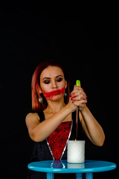 woman with creepy makeup holding knife over candle, Halloween concept 