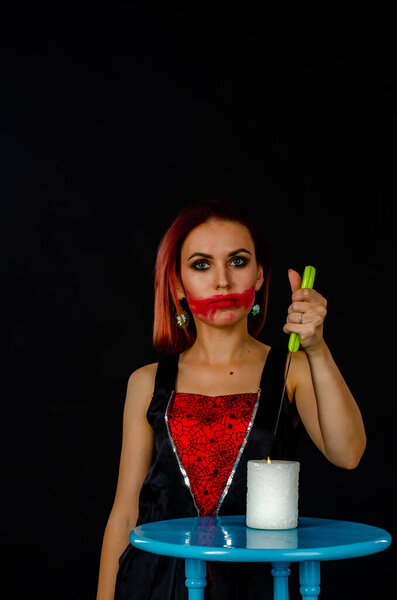 woman with creepy makeup holding knife over candle, Halloween concept 
