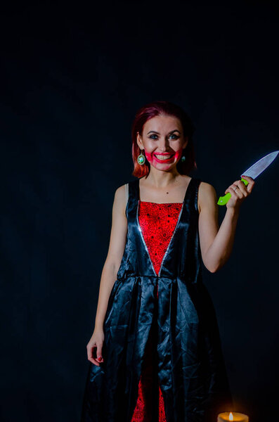 woman with creepy makeup holding knife on dark background, Halloween concept  