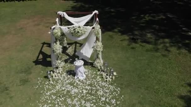 Свадебная арка из декоративных цветов на зеленом газоне. от беспилотника — стоковое видео