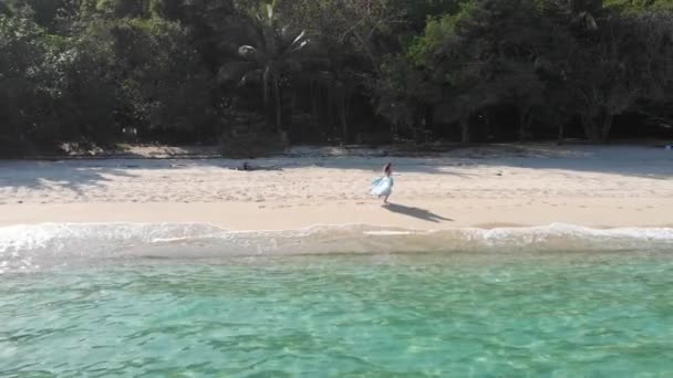 Высокая девушка в синем платье бежит и кружится вдоль пляжа у океана — стоковое видео