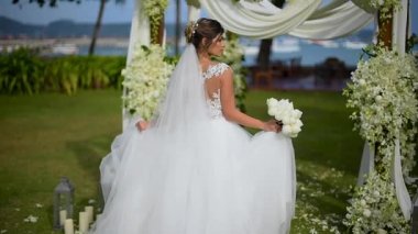 gelin düğün süslemeleri arasında duruyor, güzel kameraya bakarak geri bakıyor