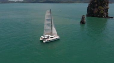 Okyanusta havadan dağlar ve yatlar ateş. Drone iki kaya arasında akar.