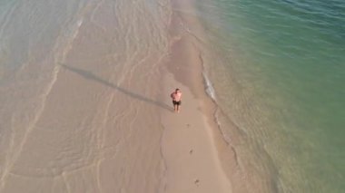 Havadan ateş Spor adam okyanus arasında kum ince bir şerit üzerinde çalışır
