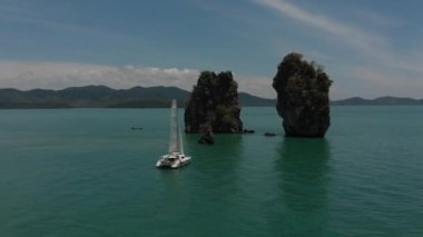 Okyanusta havadan dağlar ve yatlar ateş. Drone iki kaya arasında akar.