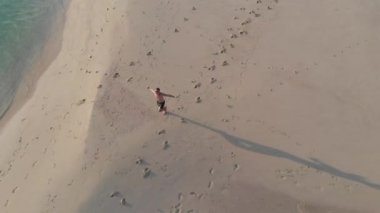 Havadan ateş Spor adam okyanus arasında kum ince bir şerit üzerinde çalışır