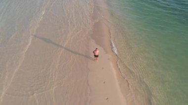 Havadan ateş Spor adam okyanus arasında kum ince bir şerit üzerinde çalışır