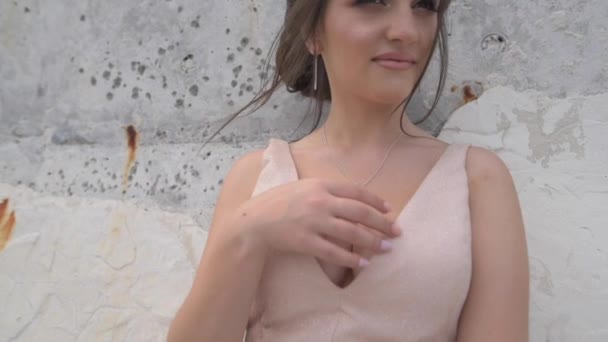 イブニングドレスの美しい女の子が壁のそばに立って 装飾の手に触れている — ストック動画
