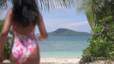 kız denize, arka görünüme, palmiye ağaçlarının etrafında koşar