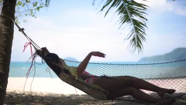 美丽的女孩躺在棕榈树的阴影下的吊床 — 图库视频影像