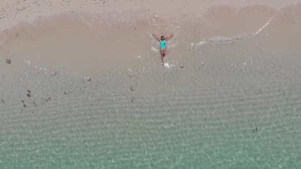 女の子はビーチに横たわって 彼女の手を広げる — ストック動画