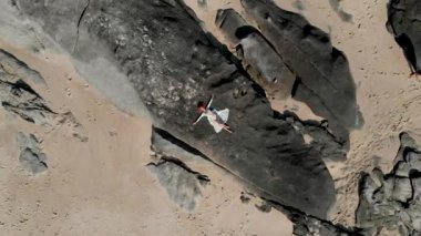 kız kayalar üzerinde yatıyor ve ellerini dalgalar