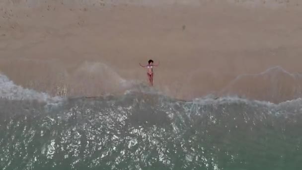 女孩躺在沙滩上 一波波从她身上滚过 — 图库视频影像