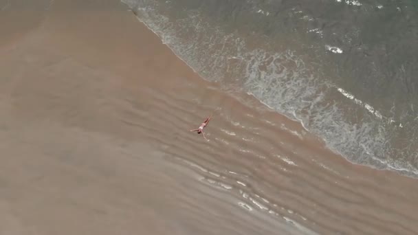 女孩躺在沙滩上 一波波从她身上滚过 — 图库视频影像