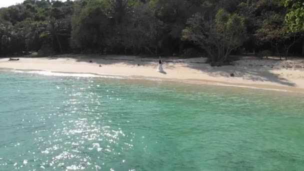 gars et fille marchent le long d'une plage vide au bord de l'océan, tenant la main 