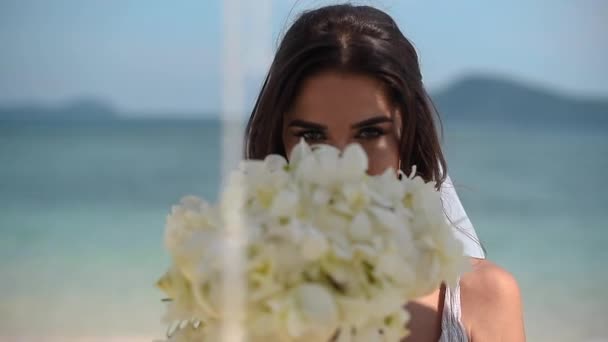 Mariée sur l'océan regarde à travers un bouquet de fleurs — Video