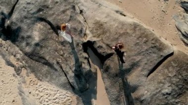 iki kız okyanus arasında kum kayalar üzerinde yürümek
