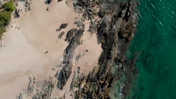 Две Девочки Лежат Песке Среди Скал Океана — стоковое видео