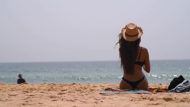 戴帽子 穿着泳衣的女孩坐在海滩上 兴高采烈 — 图库视频影像
