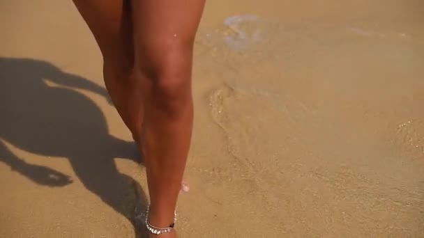 美丽的晒黑的腿沿着海边的沙滩走着 被海浪冲刷着 — 图库视频影像