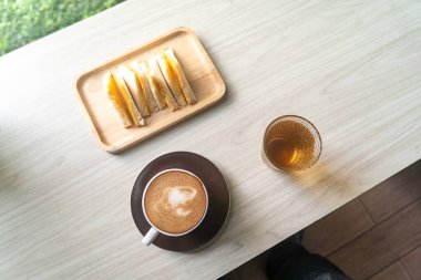 İçinde bir fincan kahve, bir bardak çay ve bir tabak sandviç olan rahat bir kafe seti. Rahatlama ve lezzetli tatların tadını çıkar..