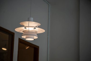 Modern bir kolye ışığı iç mekanları parlak tasarımı ve sıcak aydınlatmasıyla genişleterek evlerde veya ofislerde davetkar bir atmosfer yaratır..