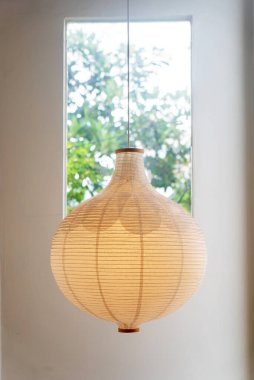 Huzurlu bir kağıt fener pencereye asılır, yumuşak ışıkla alanı aydınlatır ve odanın iç dekorunun atmosferini yükseltir..