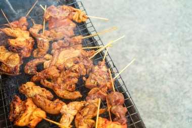 Barbekü ızgarasında cızırdayan çeşitli ızgara et şişleri ve açık hava yemeklerinin leziz lezzetlerini ve dumanlı kokusunu gözler önüne seren canlı bir sahne..