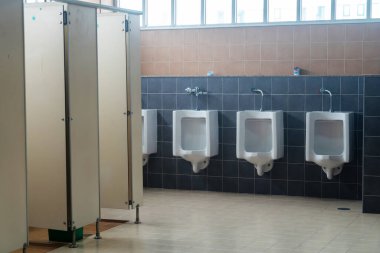 Temiz ve modern bir banyo. İçinde pisuarlar ve basit bölmeler var. Bu geniş tuvalet kamu tesislerinde hijyen ve işlevselliği vurguluyor..