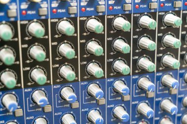 Ses karıştırma konsolu kontrollerinin detaylı görünümü, ayarlama seviyeleri, frekansları ve profesyonel ses stüdyosu ortamında efektleri gösteren düğmeler.