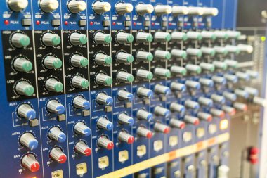 Bu resim ses mühendisliği ve müzik üretimini vurgulamak için mükemmel, canlı düğmeleri olan detaylı bir ses karıştırıcı kontrol paneli sergiliyor.