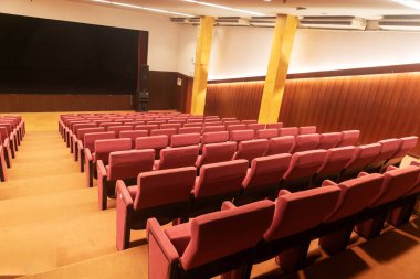 Geniş, boş, pembe koltukları gösteren, gelecekteki performanslar ve olaylar için davet edici tasarım ve ambiyansı ön plana çıkaran bir tiyatro..