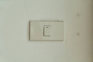 Basit bir beyaz ışık düğmesi, çağdaş iç mekanlarda minimalist tasarımı ve fonksiyonel dekorasyonu vurgulayan düz bir duvara monte edilmiştir. Ev ayarları için ideal.