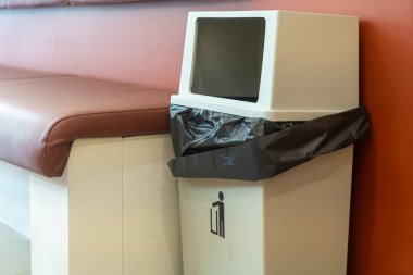 Modern iç mekanlar için tasarlanmış, parlak beyaz bir dış görünüme ve çeşitli ortamlarda etkili atık imhası için siyah bir torbaya sahip modern bir çöp kutusu..