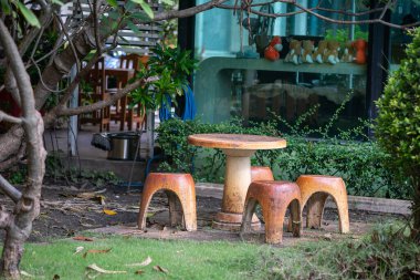 Bereketli yeşilliklerle çevrili kırsal bir masa ve tabureler içeren sakin bir açık hava ortamı, sıcak bir toplantı ya da huzurlu bir rahatlama için mükemmel..