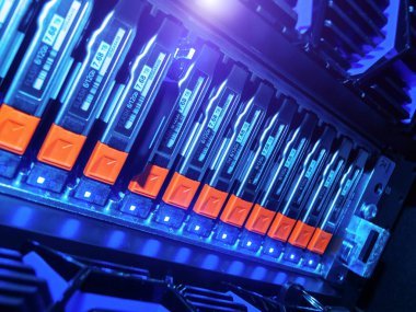 Modern bir sunucu rafındaki canlı mavi LED lambalarla aydınlatılan ileri teknoloji ve tasarım sergilenen yüksek teknoloji veri depolama birimlerinin ayrıntılı görüntüsü.