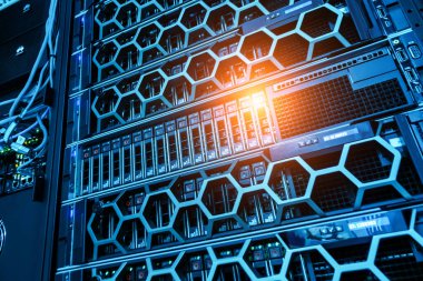 Bu resim, karmaşık ağ ekipmanları ve mavi LED ışıklandırma ve bilişim altyapısını vurgulayan bir veri merkezi içindeki modern bir sunucu rafını gösteriyor..