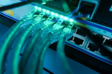 Birbirine bağlı ethernet kablolarını gösteren bir ağ anahtarının ayrıntılı yakın plan görüntüsü, modern altyapıdaki teknoloji ve dijital iletişimi vurguluyor.