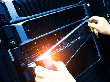 Bu resim, bir veri merkezindeki sunuculara bakım yapan bir teknisyenin ellerini gösteriyor..