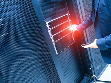 Bir iş adamı bir veri merkezinde gelişmiş sunucu teknolojisiyle etkileşime geçerek, bilişim yönetimi ve dijital altyapının modern işletmelerdeki önemini gözler önüne seriyor..