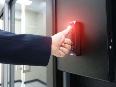 Modern ofis ortamında güvenli erişim için parmak izi tarayıcısı kullanıldığını gösteren bir el, güvenlik sistemlerindeki teknoloji ve kullanıcı etkileşimini vurguluyor.