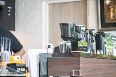 Canlı bir kafe tezgahında kahve öğütücüsü, demleme ekipmanı ve rahat bir ortam modern ortamlarda sosyalleşmek ve kaliteli içeceklerden zevk almak için mükemmel..